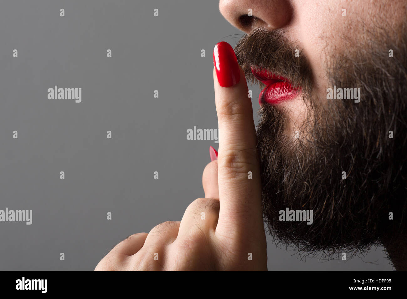 bearded-man-with-red-lipstick-on-his-lips-and-nail-polish-making-silence-HDPF95.jpg